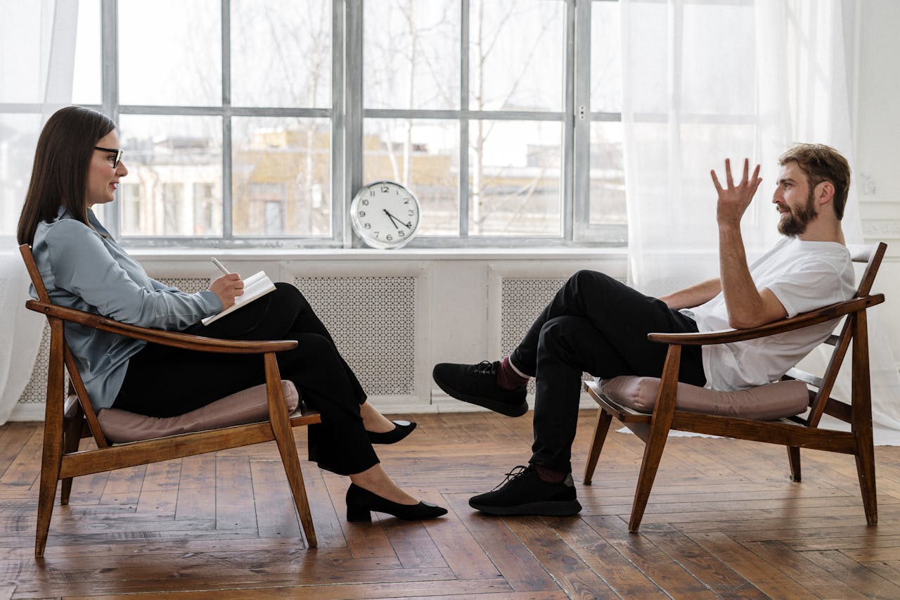 Services-01 A therapist engaging in a counseling session with a male patient to support mental health.